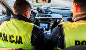 zdjęcie kolorowe: dwóch policjantów wydziału ruchu drogowego w policyjnym radiowozie