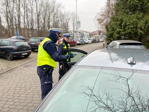 zdjęcie kolorowe: dwóch policjantów katowickiej drogówki podczas kontroli samochodu osobowego