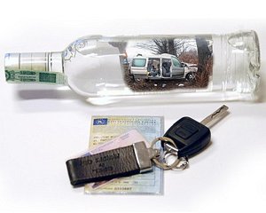 zdjęcie kolorowe: przewrócona butelka po wódce i kluczyki samochodowe