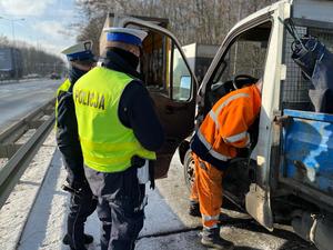zdjęcie kolorowe: policjant katowickiej drogówki z inspektorem Wojewódzkiego Inspektoratu Transportu Drogowego w Katowicach podczas kontroli drogowej pojazdu ciężarowego