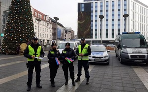 zdjęcie kolorowe: funkcjonariusz Policji, Wojewódzkiego Inspektoratu Transportu Drogowego i straży miejskiej stojący na placu przed zaparkowanymi pojazdami służbowymi podczas działań &quot;Błyśnij dla życia&quot;