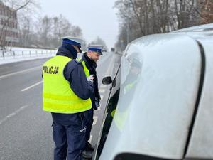 zdjęcie kolorowe: dwóch policjantów katowickiej drogówki podczas kontroli pojazdu osobowego