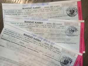 zdjęcie kolorowe: trzy druki mandatów karnych z zamazanymi danymi osób ukaranych
