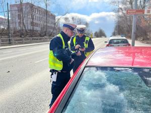 zdjęcie kolorowe: dwóch policjantów wydziału ruchu drogowego podczas działań NURD rozmawiający z kierującym samochodu osobowego