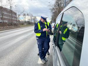 zdjęcie kolorowe: zdjęcie kolorowe: dwóch policjantów wydziału ruchu drogowego przeprowadzający kontrolę drogową wobec kierującego samochodem osobowym