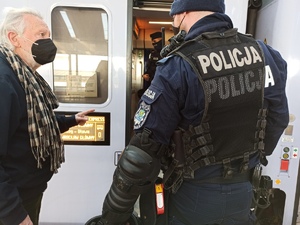 zdjęcie kolorowe: policjant rozmawiający z mężczyzna na peronie przed pociągiem