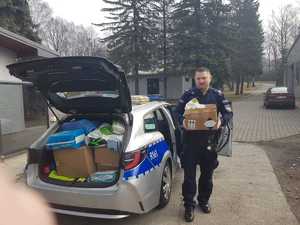 zdjęcie kolorowe: policjant niosący pudełko z darami