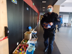 zdjęcie korowe: policjant niosący pudełko ze słodyczami