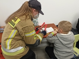 zdjęcie kolorowe funkcjonariuszka straży pożarnej rozmawiająca z małym chłopce o jego bezpieczeństwie