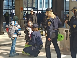 zdjęcie kolorowe: katowiccy policjanci przekazujący bransoletki niezgubki dzieciom znajdującym się na dworcu