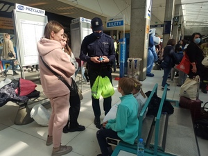 zdjęcie kolorowe: policjant rozmawiający z matka dwójki dzieci o ich bezpieczeństwie