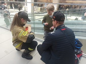 zdjęcie kolorowe: strażaczka rozmawiająca z ojcem i synem dna katowickim dworcu