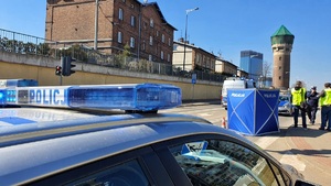 zdjęcie kolorowe: policyjny radiowóz i parawan rozłożony na przejściu dla pieszych oraz policjanci