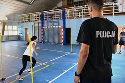 zdjęcie kolorowe: sala gimnastyczna, na której kobieta biegnie po torze sprawnościowym nadzorowana przez policyjnego instruktora
