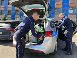 zdjęcie kolorowe: katowiccy policjanci pakujący dary do radiowozu
