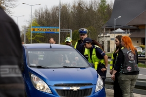 zdjęcie kolorowe: policjant i policjantka katowickiej komendy wspólnie z członkami stowarzyszenie Moto Pistons Górny Śląsk podczas rozmowy z kierującym samochodem osobowym