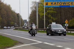 zdjęcie kolorowe: motocykl i samochód osobowy poruszający się po jezdni