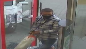 zdjęcie kolorowe: mężczyzna w średnim wieku wchodzący do sklepu, ubrany w biało-niebieska koszulę w kratę i niebieskie spodnie jeansowe. Na twarzy maseczka ochronna.