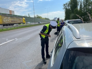 zdjęcie kolorowe: policjant katowickiej drogówki podczas kontroli drogowej rozmawia z kierującym samochodem osobowym