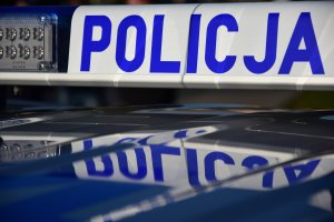 zdjęcie kolorowe: dach radiowozu na którym umieszczony jest sygnał świetlny z napisem o treści Policja