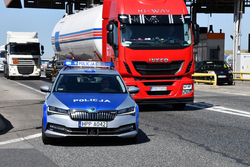 zdjęcie kolorowe: na pierwszym tle zaparkowany policyjny radiowóz, na drugim tle ciężarówka typu cysterna, zatrzymana do kontroli drogowej