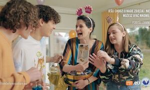 zdjęcie kolorowe: dwie młode dziewczyny i dwóch młodych chłopaków, którzy stoją wokół stołu i przyglądają się zdjęciu