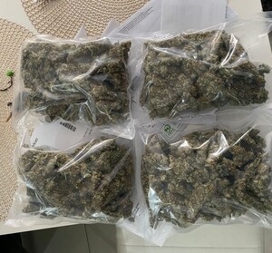 zdjęcie kolorowe: na blacie stołu cztery worki zamykane próżniowe z wysuszaną w środku marihuaną