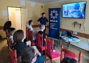 zdjęcie kolorowe: katowicki dzielnicowy ogląda razem z ukraińską młodzieżą przygotowane przez Komendę Główną Policji materiały dotyczące handlu ludźmi