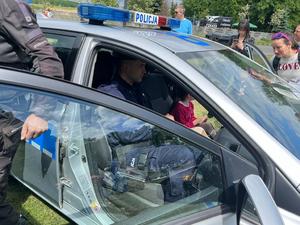 zdjęcie kolorowe: policjant podczas pikniku pokazujący dzieciom radiowóz