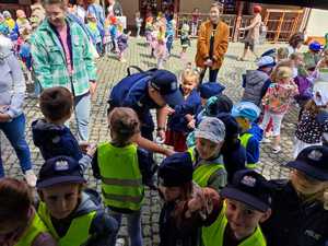 Zdjęcie kolorowe: policjant rozdający dzieciom nagrody za udział w konkursach