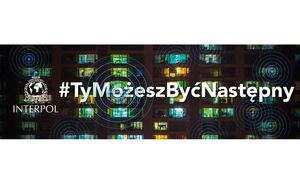 zdjęcie kolorowe: plakat przedstawiający zapalone światła w mieszkanich znajdujących sie w bloku mieszkalnym oraz znak graficzny INTERPOL-u, oraz napis o treści INTERPOL #TyMożeszByćNastępny