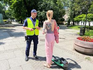 zdjęcie kolorowe: policjant rozmawiający o bezpieczeństwie z kobietą, która poruszała się hulajnogą