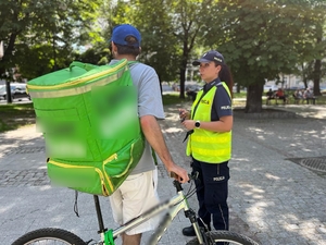 zdjęcie kolorowe: policjantka rozmawiająca z rowerzysta o bezpieczeństwie w ruchu drogowym