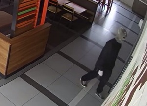 zdjęcie kolorowe: mężczyzna z założoną na twarz komiarką wchodzi do restauracji