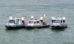 zdjęcie kolorowe: na jeziorze trzy policyjne motorówki z policjantami na pokładzie
