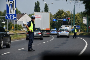 zdjęcie kolorowe; policjant drogówki zabezpieczający przejazd kolarzy podczas wyścigu
