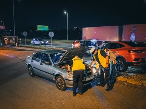 zdjęcie kolorowe: policjanci drogówki podczas kontroli stanu technicznego pojazdu osobowego