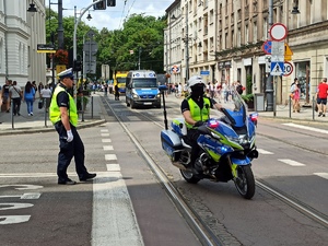 zdjęcie kolorowe:   policjant  katowickiej drogówki na motorze służbowych i policjant drogówki kierujący ruchem na skrzyzowaniu