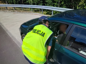 zdjęcie kolorowe: policjantka rozmawiająca z kierującym samochodem osobowym
