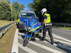 Zdjęcie kolorowe przedstawia policjanta przy motocyklu policyjnym.