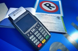 zdjęcie kolorowe: terminal płatniczy i bloczek z drukami mandatów karnych kredytowanych