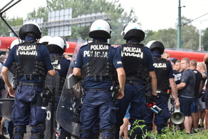 zdjęcie kolorowe: policjanci oddziału prewencji przygotowujący się do przeprowadzenia kibiców
