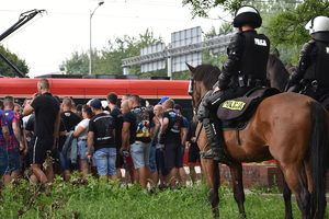 zdjęcie kolorowe: policjanci na koniach nadzorujący kibiców podczas przejścia na stadion