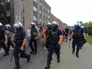 zdjęcie kolorowe: policjanci oddziau prewencji prowadzący ulicami Katowic pseudokibiców na stadion