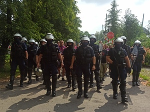 zdjęcie kolorowe: policjanci oddziału prewencji prowadzący przez Park Śląski kibiców na stadion GKS-U
