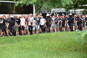 zdjęcie kolorowe: przemarsz kibiców przez Park Śląski na stadion katowickiej drużyny w asyście policjantów oddziału prewencji