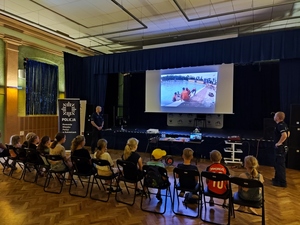 zdjęcie kolorowe: dwóch dzielnicowych i dzieci oglądający spot przygotowany przez katowickich policjantów dotyczący bezpieczeństwa nad wodą
