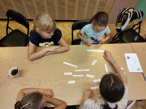 zdjęcie kolorowe: dzieci siedzące przy stole i układające zdania z tak zwanej rozsypywanki