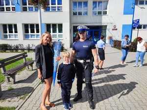 zdjęcie kolorowe: policjant drogówki z uczniem i jego mama podczas pamiątkowego zdjęcia