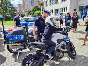 zdjęcie kolorowe: dwóch policjantów katowickiej drogówki przy swoich motorach służbowych, które prezentowane są uczniom pierwszej klasy
